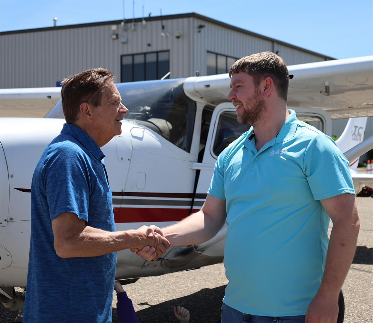 Rob Kreibich shaking hands with a voter in front of a small airplane