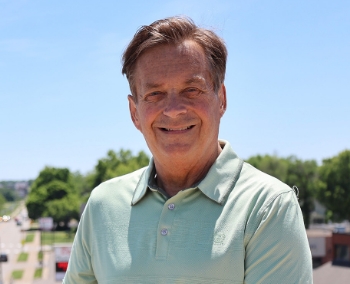 Rob Kreibich smiling with a road and trees in the background