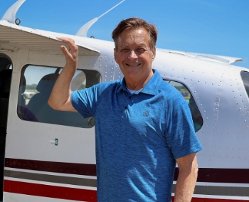 Rob Kreibich smiling with his hand on the wing of an airplane